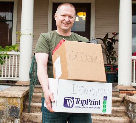 Man smiling with boxes of items to donate to Goodwill