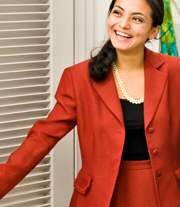 Smiling young woman trying on a red business suit at Goodwill