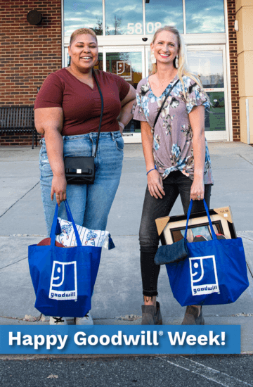 Two woman with blue Goodwill reusable bags smiling outside of a Goodwill store