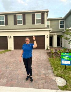 Paola stands outside of her new home