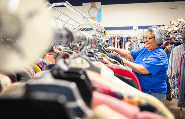 Goodwill employee hangs clothing on the rack